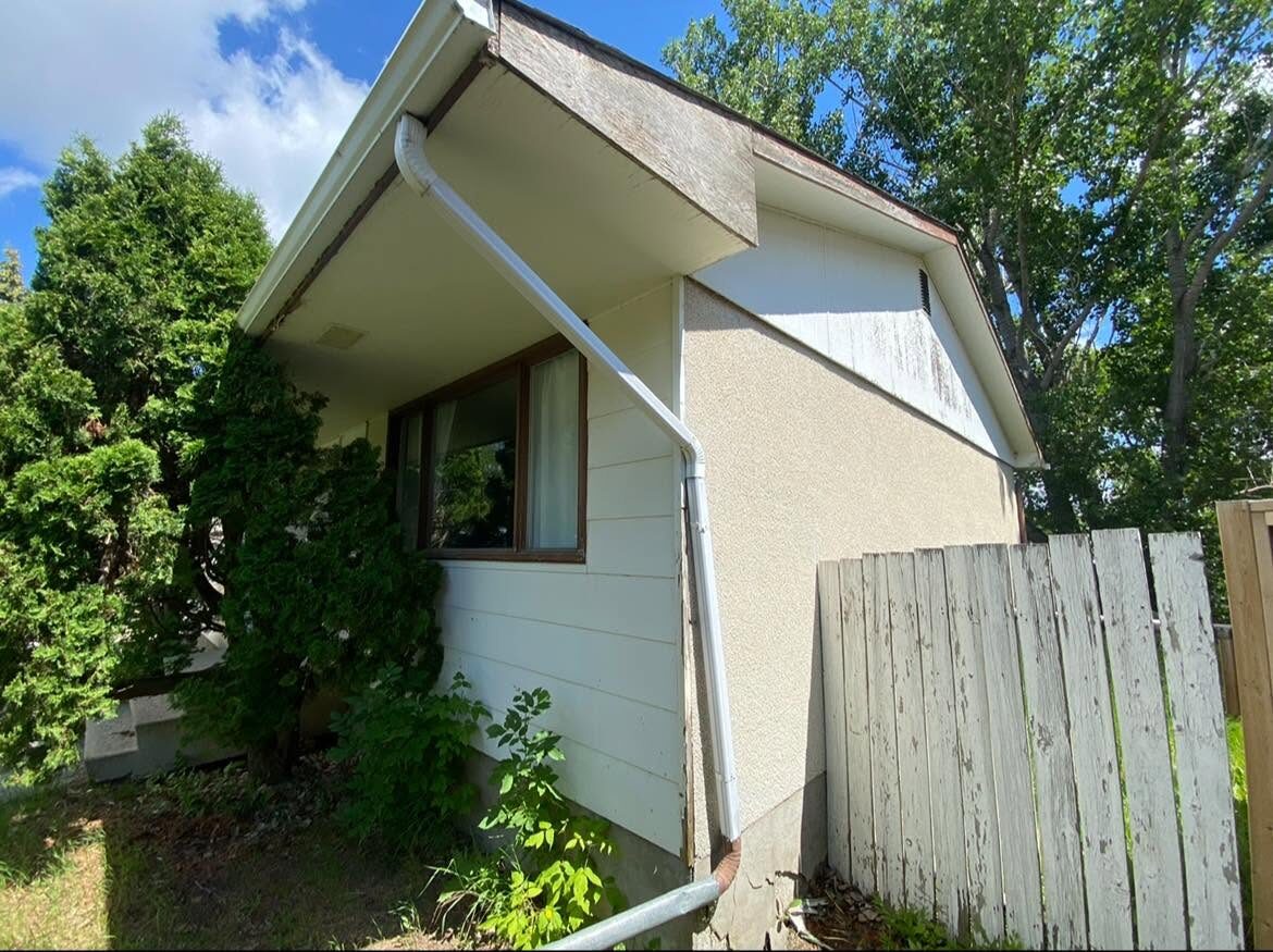 Exterior before — worn siding and overgrown yard