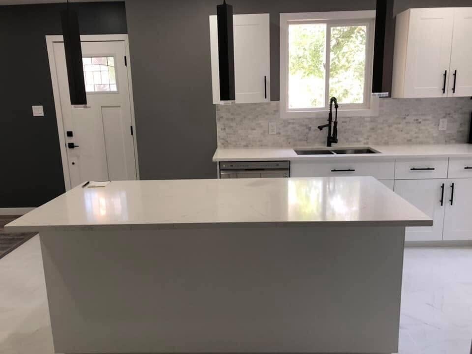 Kitchen after renovation — white shaker cabinets and quartz island